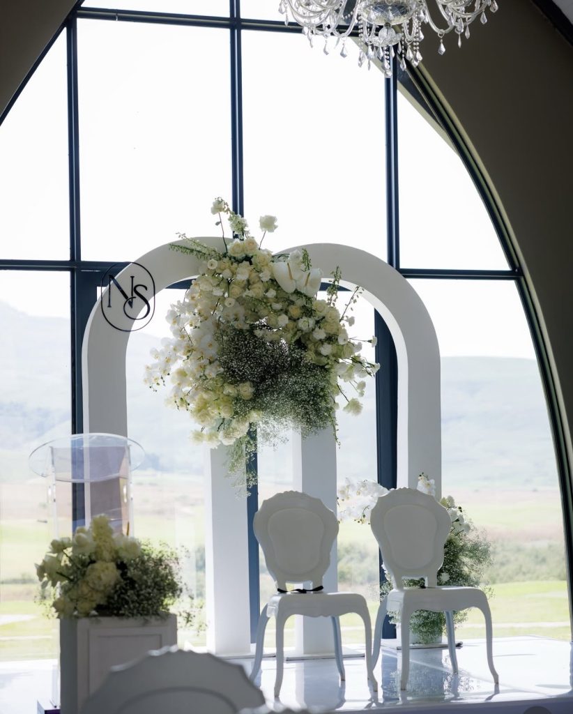 White floral wedding ceremony arch with chairs by Fems Events