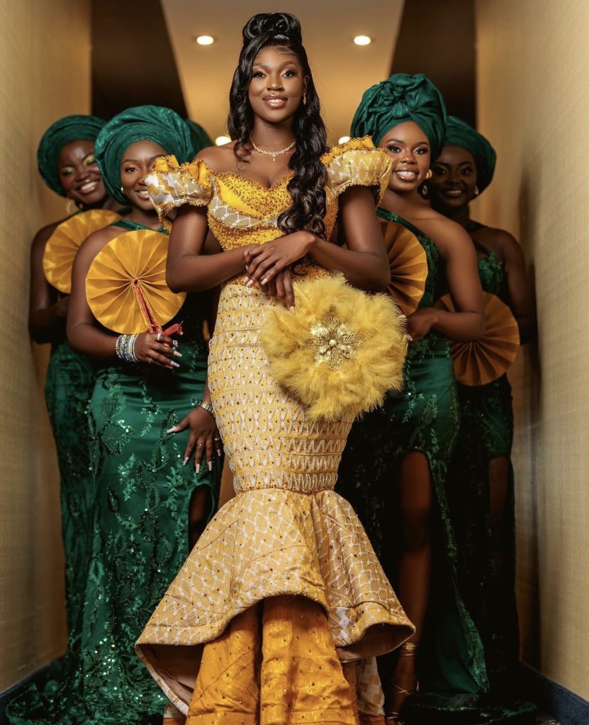 African traditional bride in a gold gown with bridesmaids in green and yellow