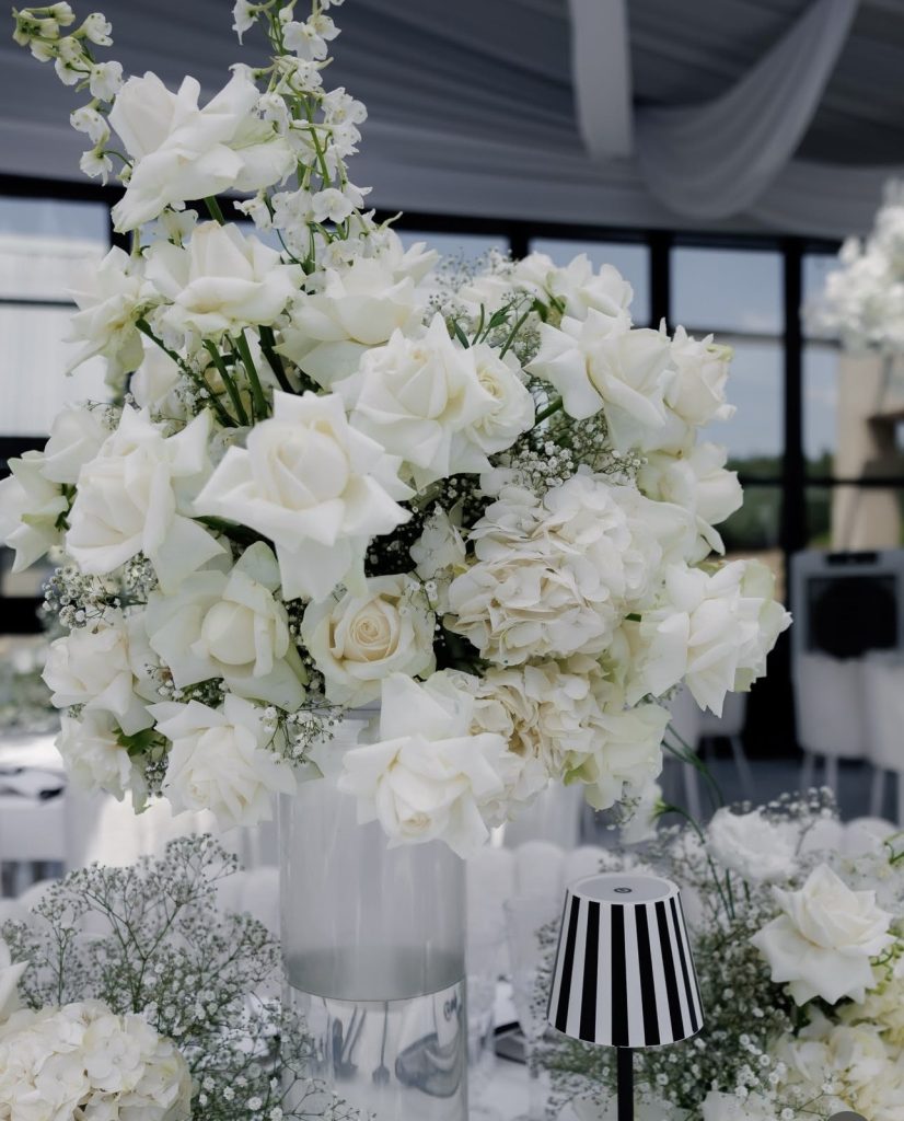Lush white wedding floral arrangement on a reception table by Fems Events