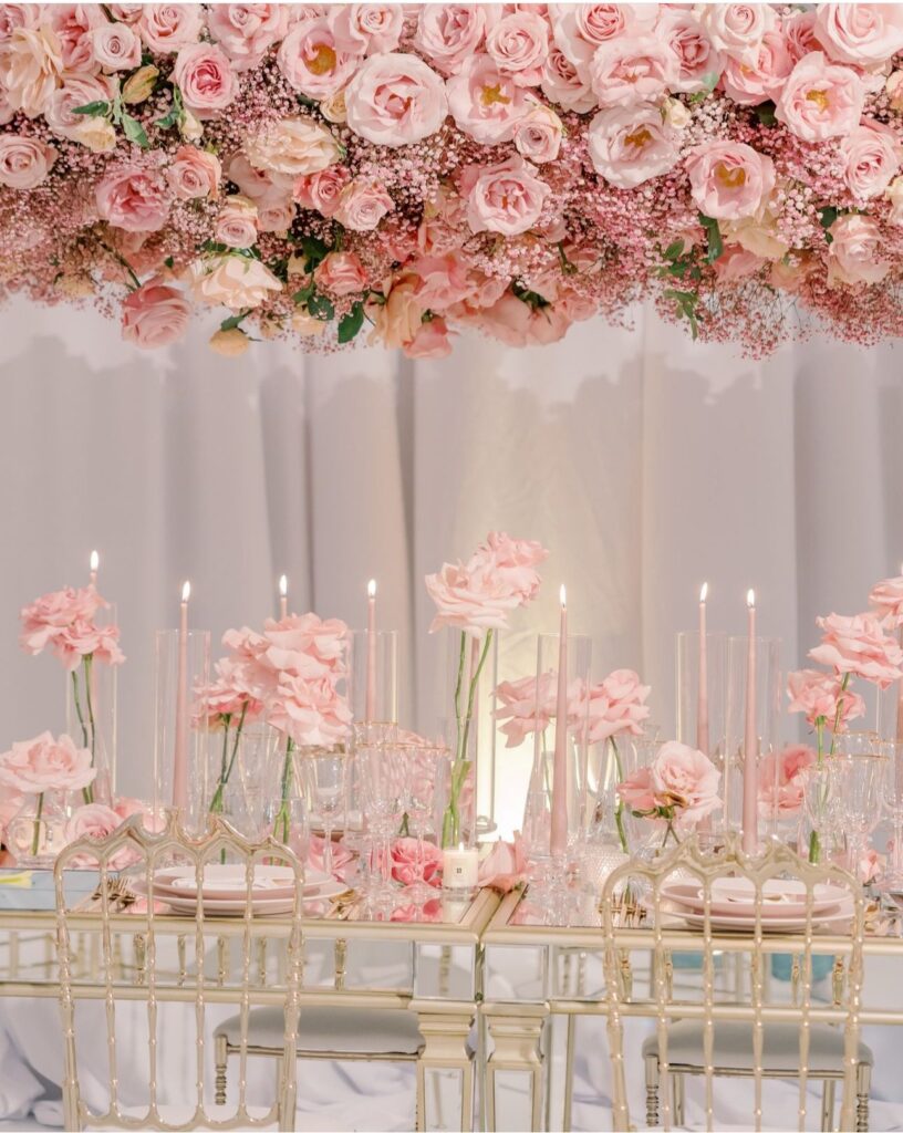 Suspended pink rose installation over a mirrored head table by Fems Events