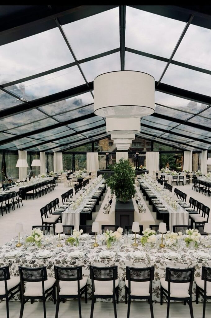 Glass tent reception with long floral tables by Fems Events