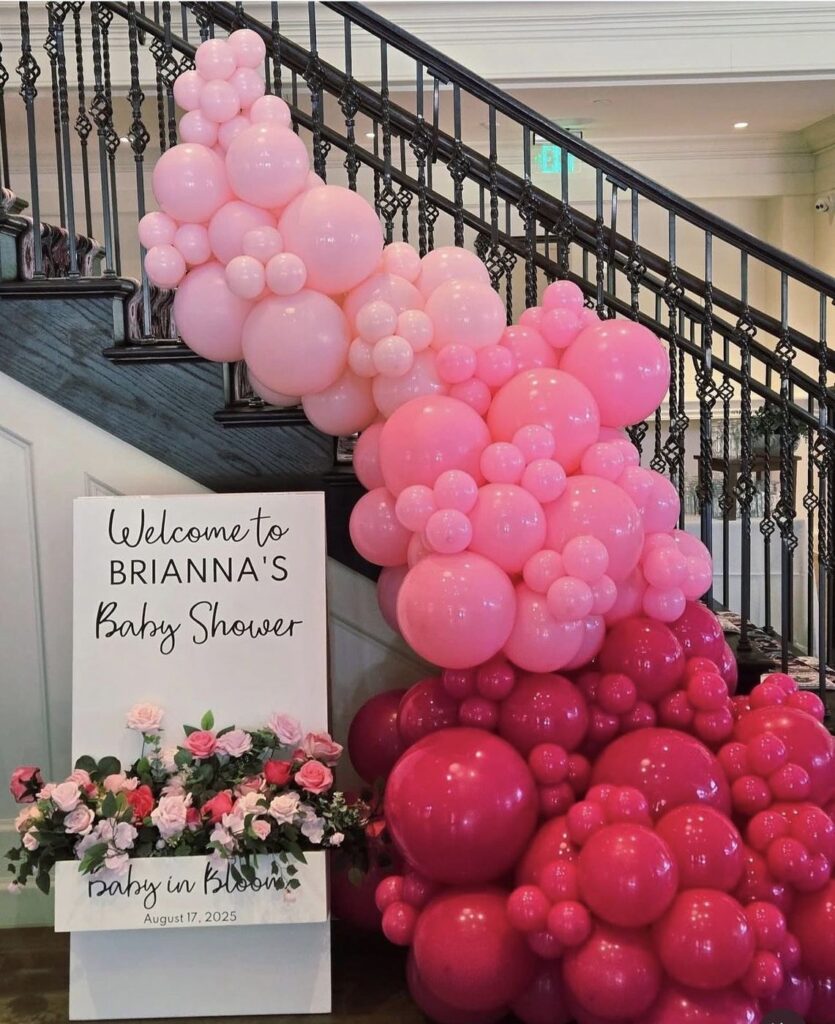 Pink balloon staircase and floral welcome sign for a baby shower by Fems Events